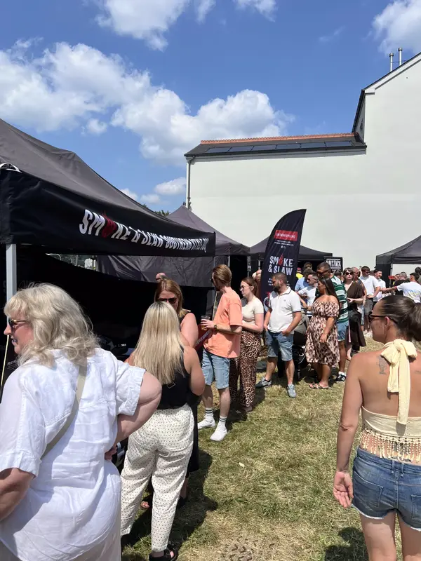 A queue of people waiting at the Smoke & Slaw stand at a festival