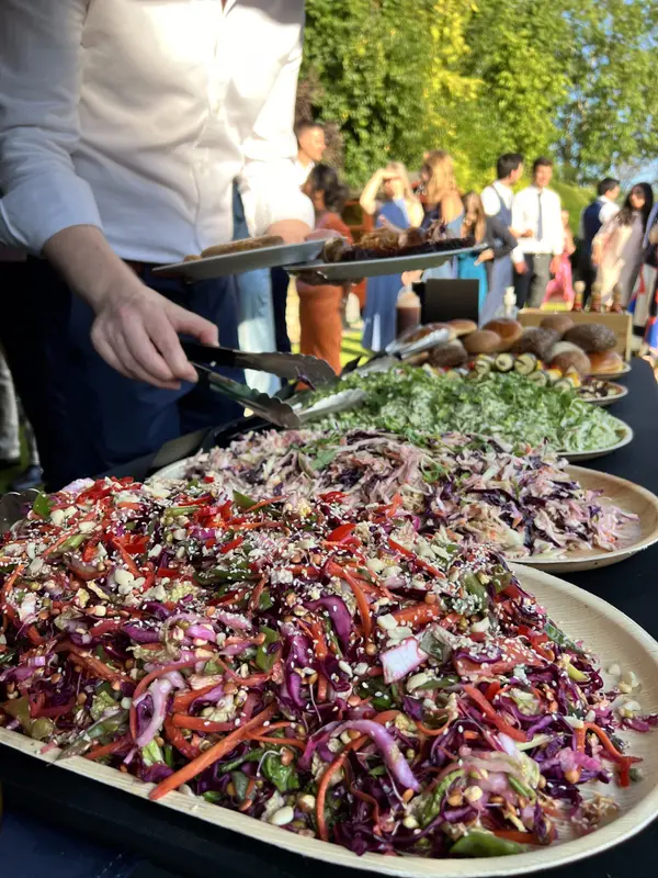 A large platter of slaw with guests queuing behind