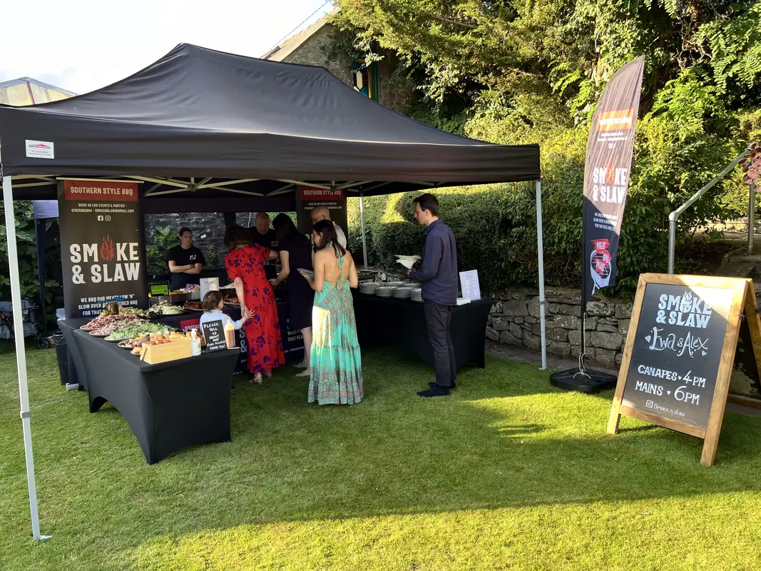 Guests arriving at the Smoke & Slaw gazebo in a garden