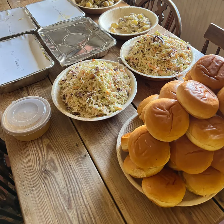 Apple slaw, potato salad and buns set out for a wedding buffet